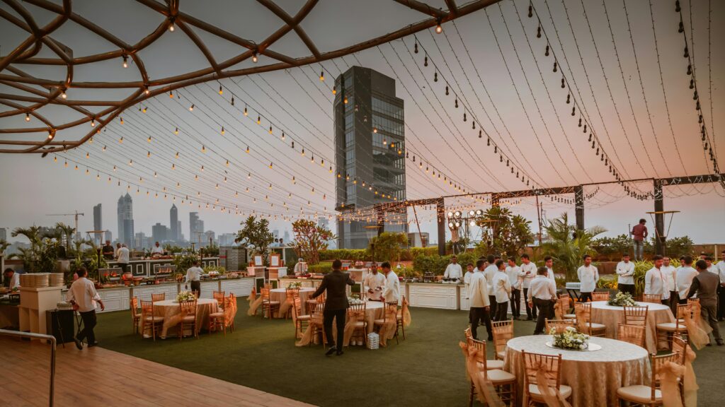 pexels-photo-3835638-3835638 Elegant rooftop event with tables and lights set against Mumbai skyline at sunset, India.